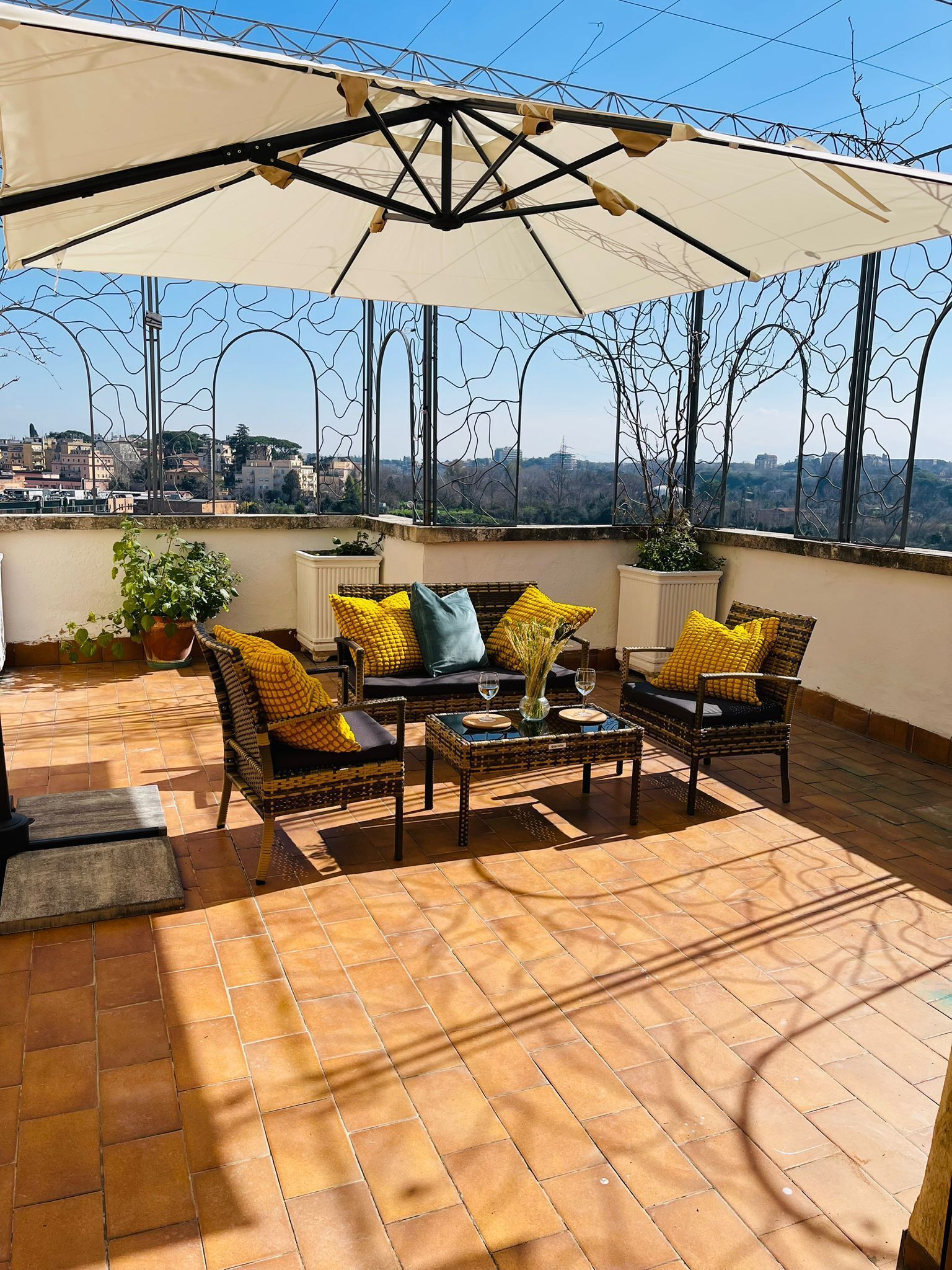 A rooftop terrace with outdoor furniture, a large umbrella, and a view of the cityscape.