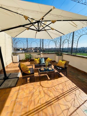 Una terrazza con mobili da esterno, un ombrellone grande e vista sulla città.