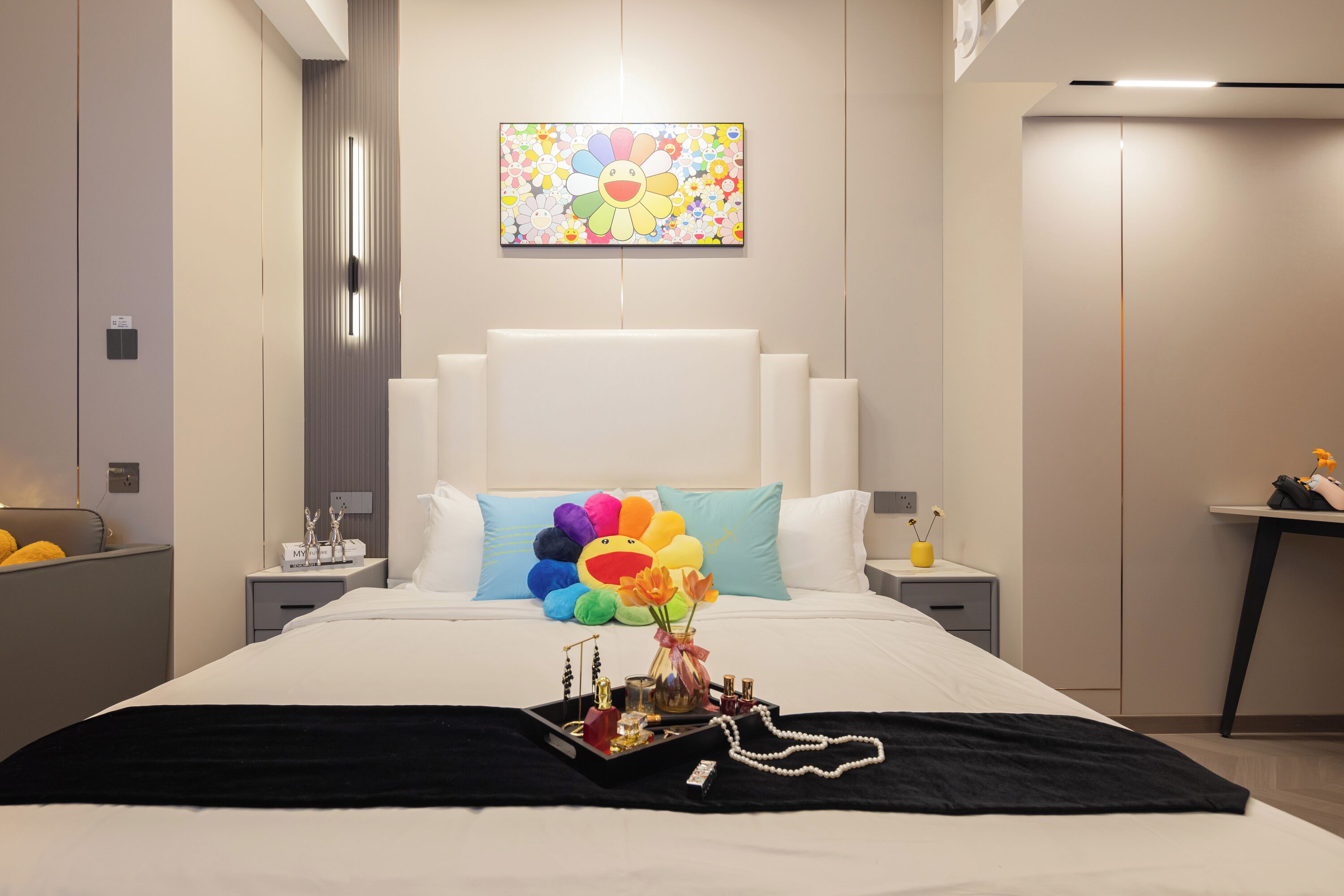 Una camera da letto moderna con un letto grande, un bouquet decorativo e un'opera d'arte appesa al muro.