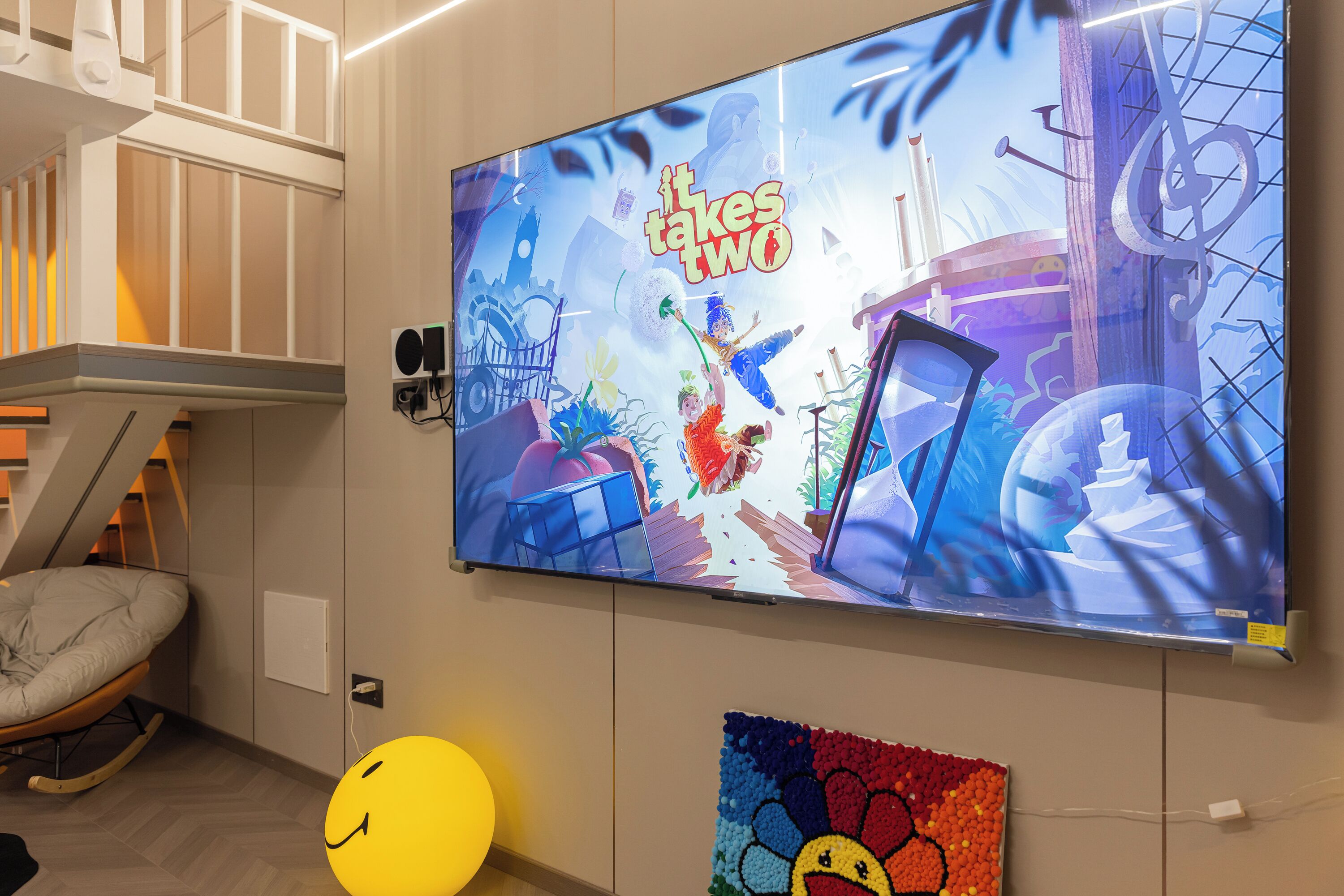 A television screen displaying 'The Tale of Two Cities' with a colorful animation, a white chair, a yellow smiley face balloon, and a wall-mounted speaker.