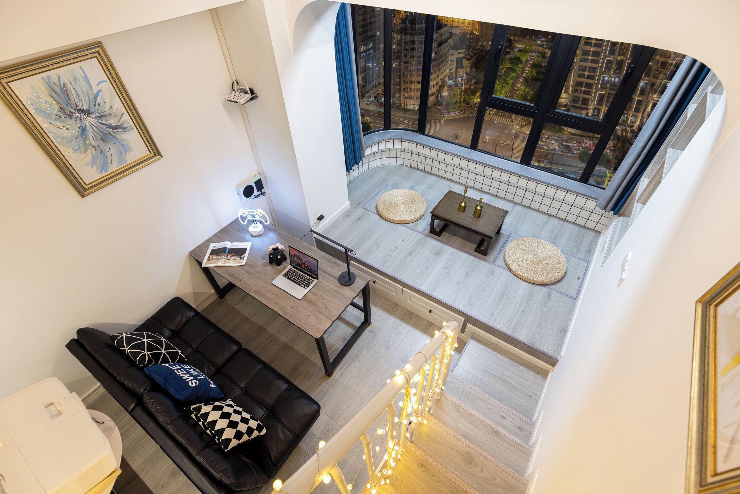 Un interior moderno con zona de comedor, un sofá y vista a un paisaje urbano a través de ventanas amplias.