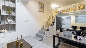 A modern interior with a staircase, a dining area with a laptop and gaming controller, and a living space with a sofa and decorative items. - ShanghaiHills&SunflowerUltraHorizonHotel (Shanghai)