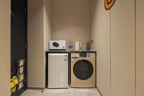 A compact kitchenette with a microwave, a small refrigerator, and a washing machine. - ShanghaiHills&SunflowerUltraHorizonHotel (Shanghai)