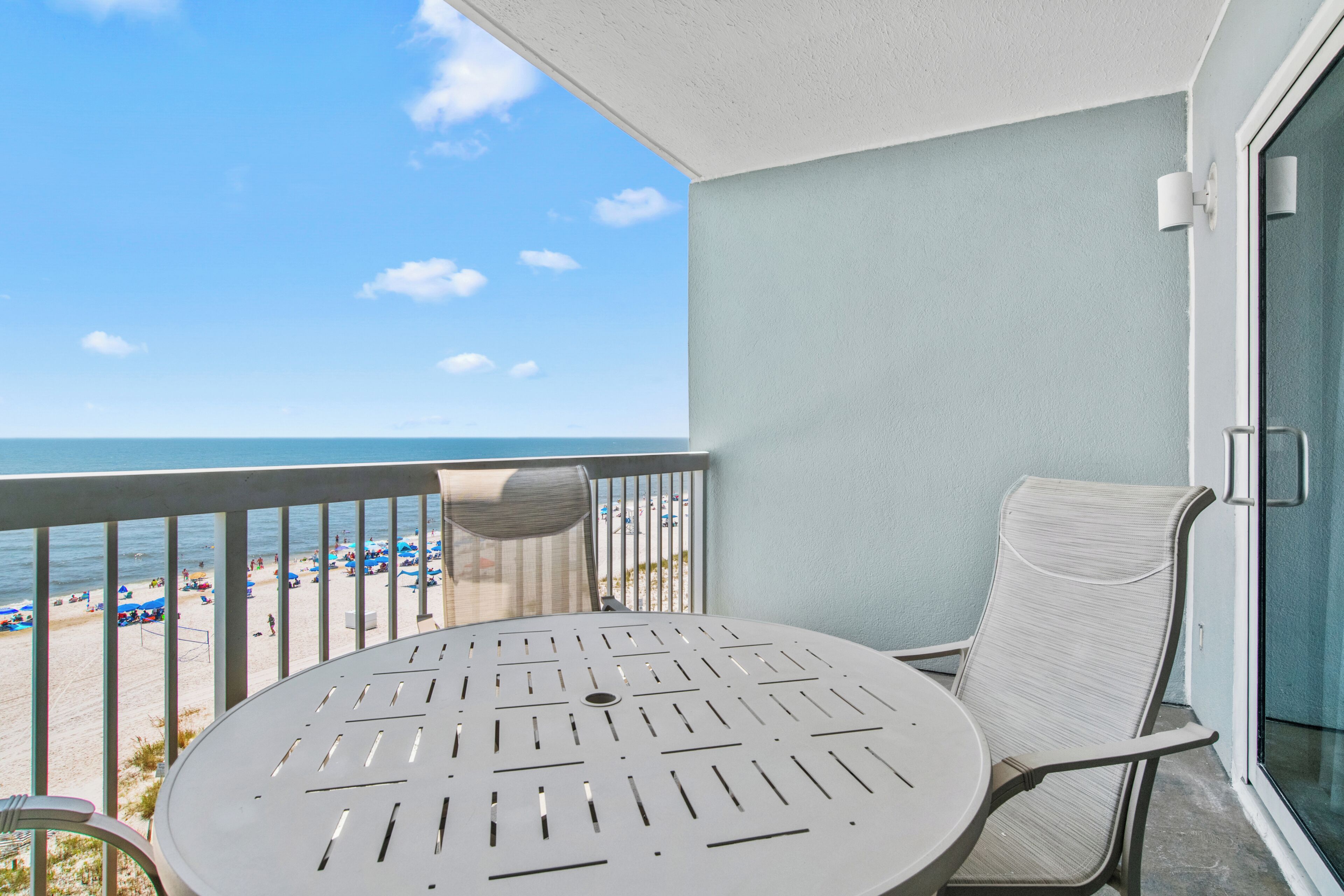 Ein Balkon mit Blick auf den Strand, ein runder Tisch und ein Stuhl.