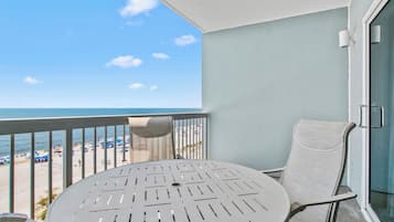 Un balcón con vistas a la playa, una mesa redonda y una silla.