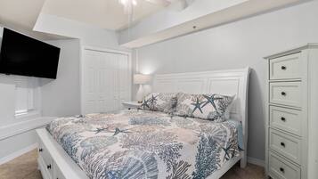 A bedroom with a bed, nightstands, a dresser, a television, and a ceiling fan.