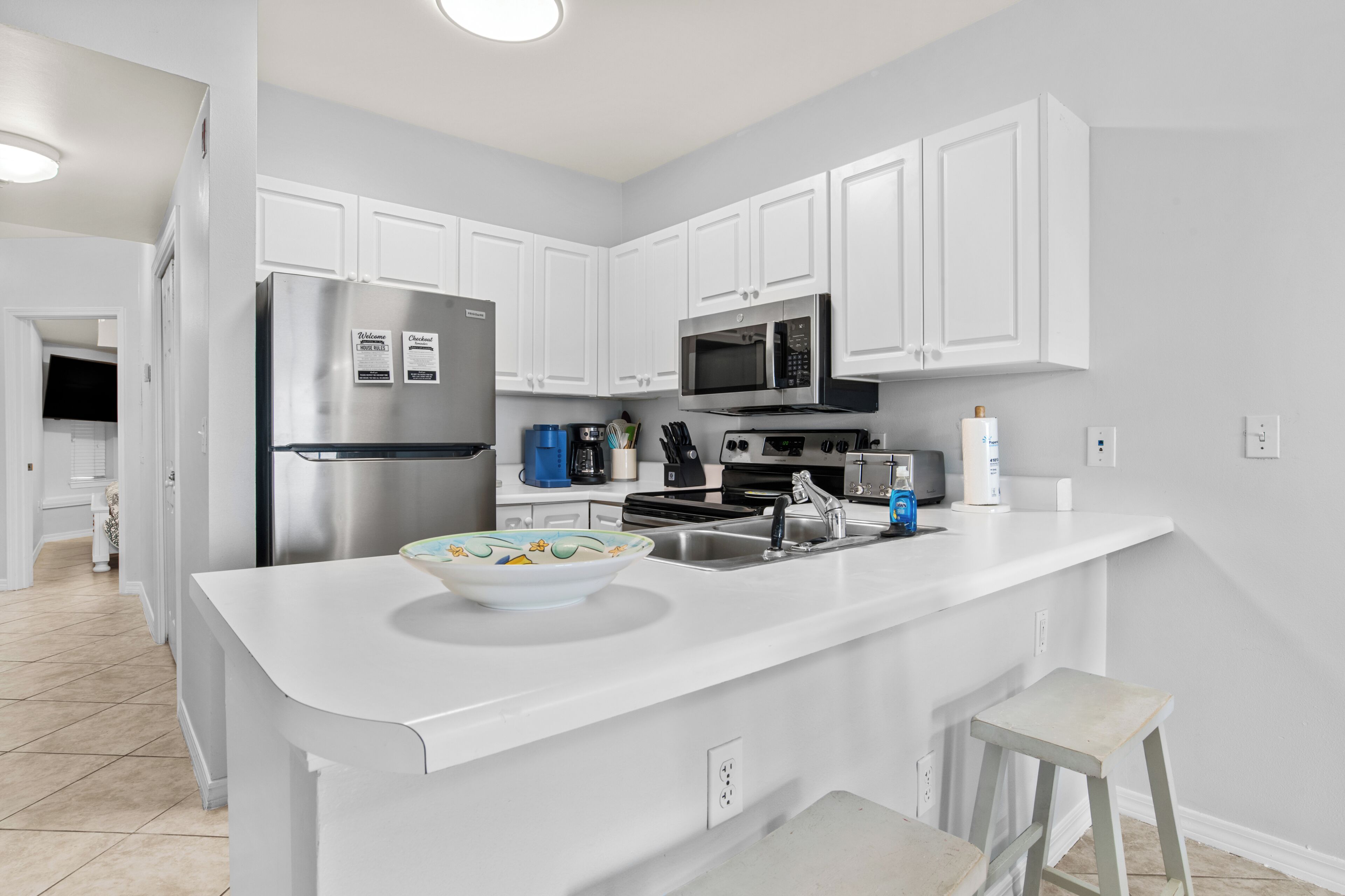 A modern kitchen with white cabinetry, stainless steel appliances, and a large island with a bowl.