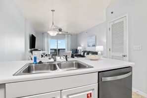 Eine moderne Küche mit doppelter Spüle, Deckenventilator und Blick auf den Balkon.