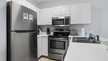 A modern kitchen with stainless steel appliances, white cabinetry, and a built-in microwave.