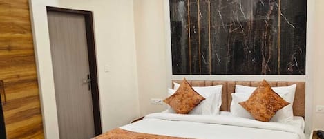 Habitación de hotel con una cama grande, cabecera de madera, pared con diseño de mármol, un sillón de cuero marrón y una mesita.