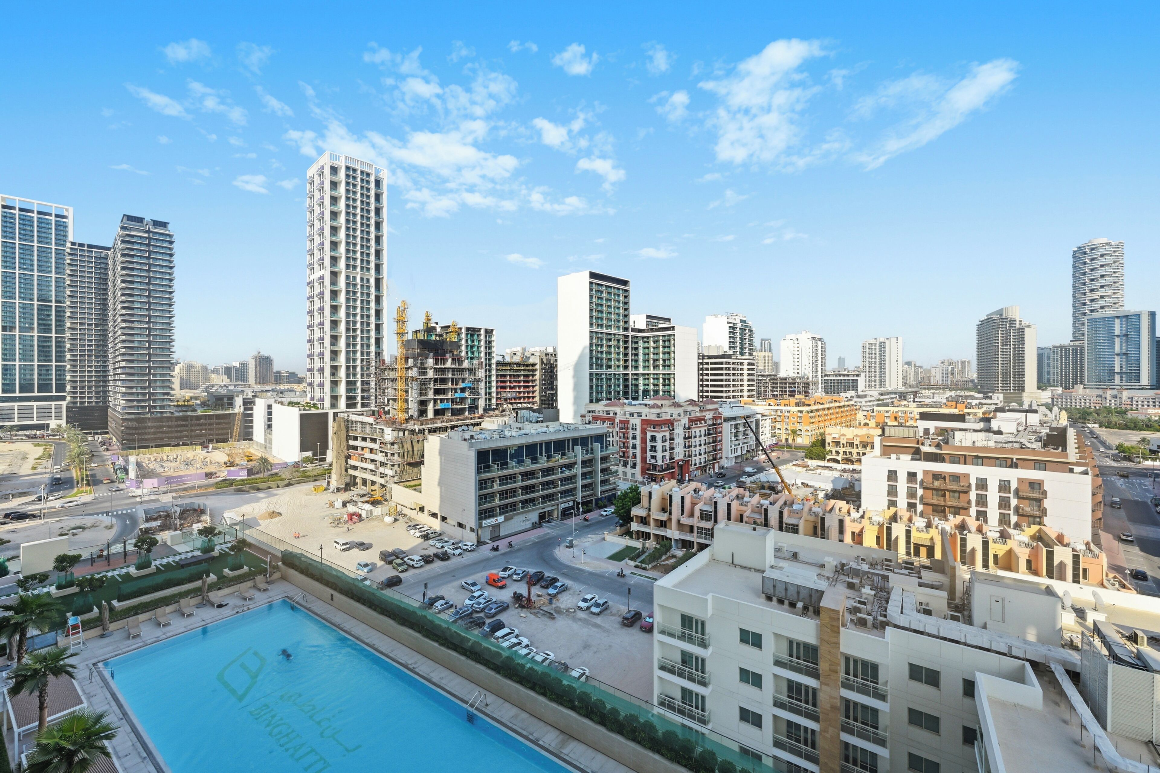 A high-rise building with multiple floors, a swimming pool, and surrounding urban infrastructure.