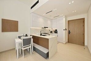 A modern kitchen with white cabinetry, a marble countertop, and a built-in stove. - Bloomfields 1BR in Binghatti Onyx  (Dubai)