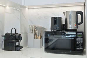 A kitchen with a microwave, a coffee maker, and a kettle. - Bloomfields 1BR in Binghatti Onyx  (Dubai)
