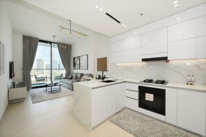 A modern kitchen with white cabinetry, a marble countertop, and a built-in oven. - Bloomfields 1BR in Binghatti Onyx  (Dubai)