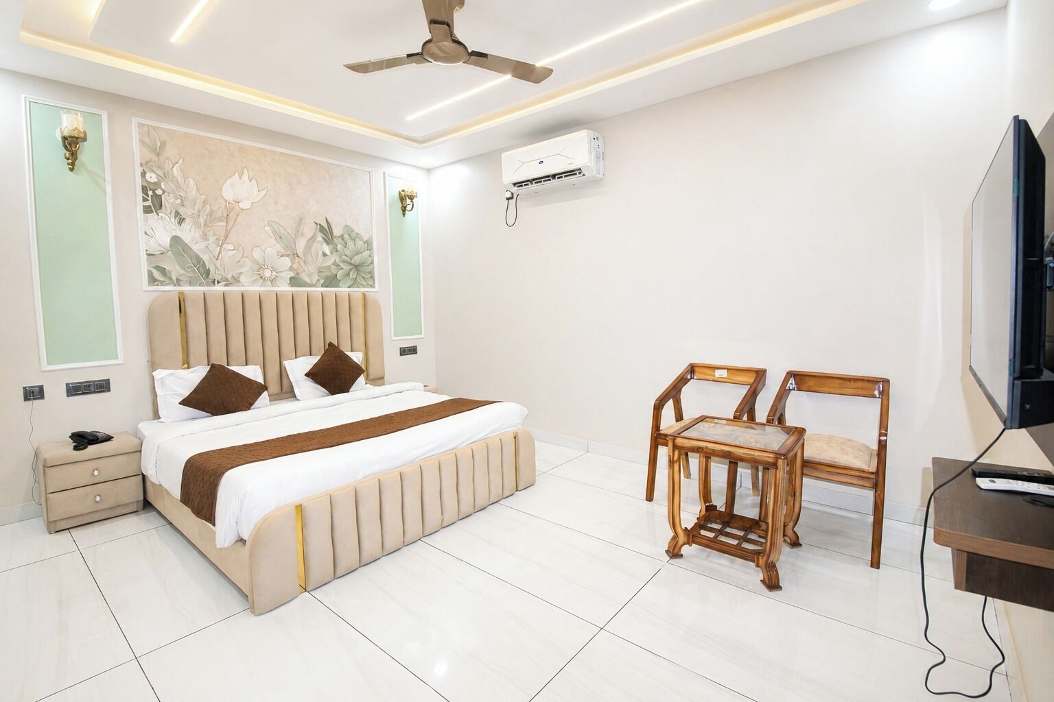 A modern hotel room with a bed, bedside tables, a desk, a chair, and a television.