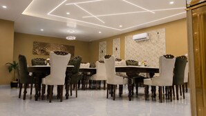 Een eetgedeelte met een modern plafondontwerp, een ronde centrale tafel en meerdere stoelen.