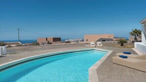 A swimming pool with a clear view of the sea and buildings in the background. - Solis Akrotiri Villa (Santorini)