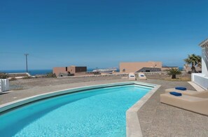 A swimming pool with a clear view of the sea and buildings in the background. - Solis Akrotiri Villa (Santorini)