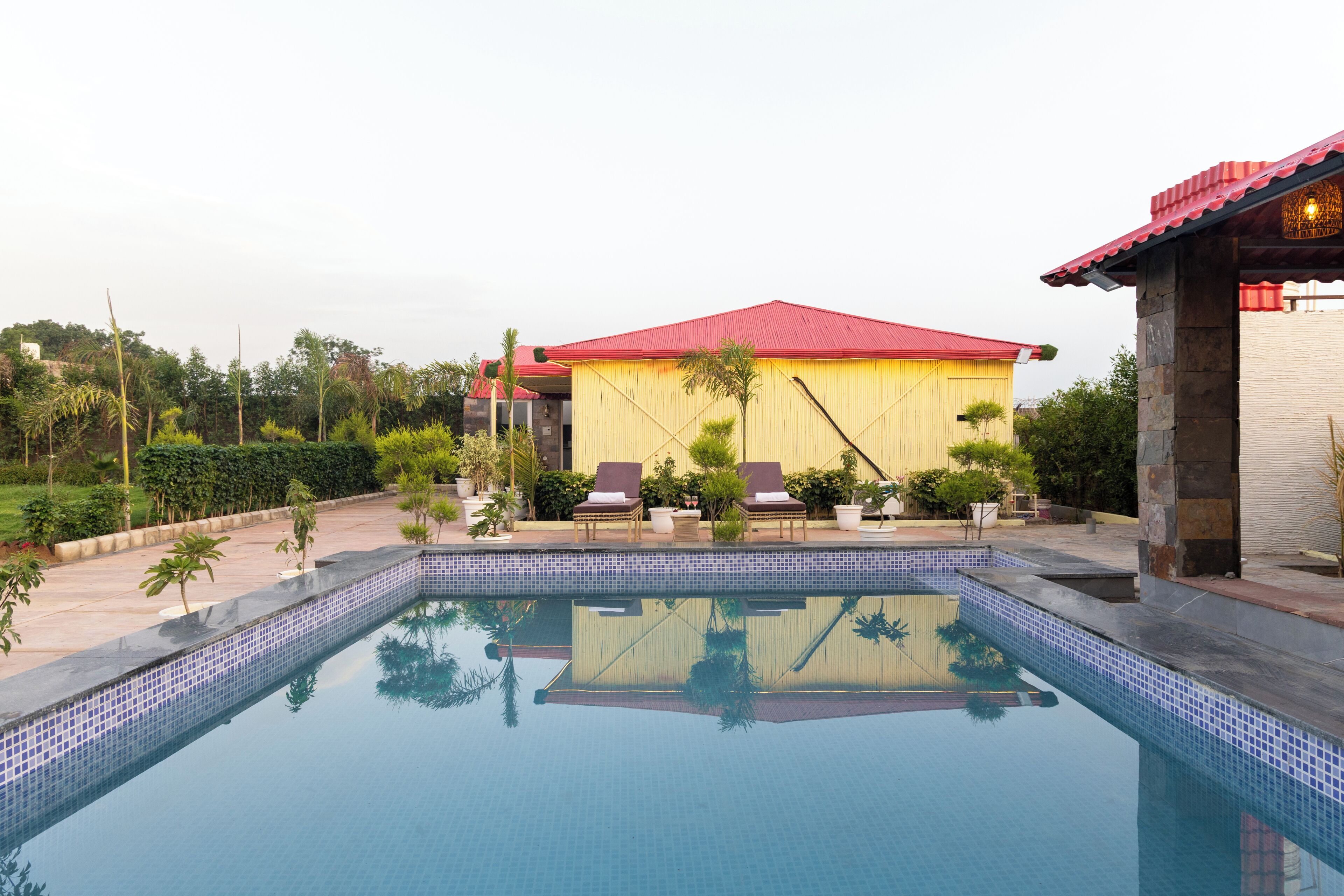 A swimming pool with lounge chairs and a building with a red roof.