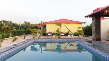 A swimming pool with lounge chairs and a building with a red roof.