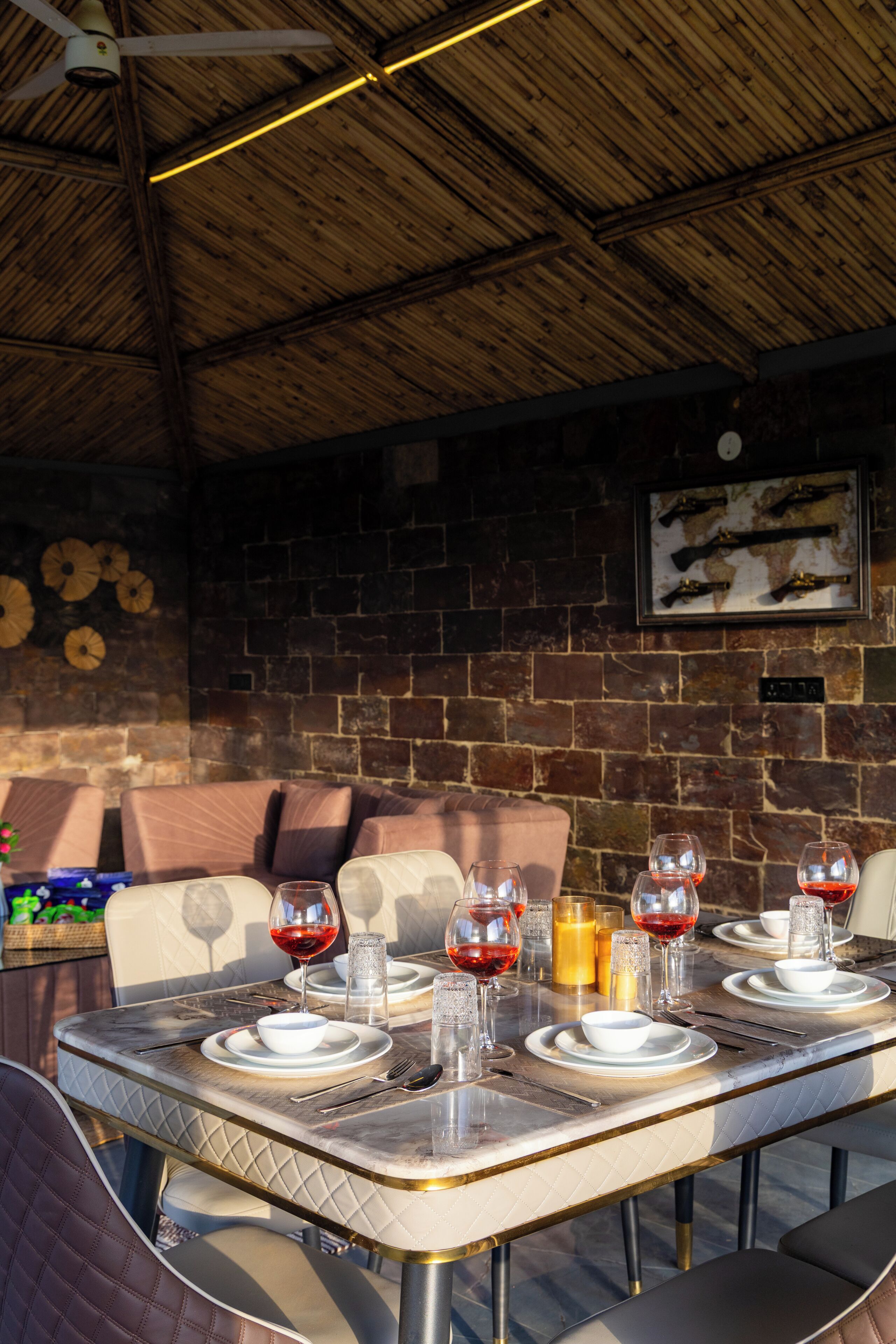 An outdoor dining area with a brick wall, a ceiling fan, and a framed map on the wall.