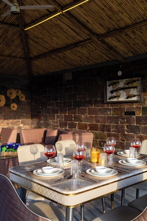 Un área de comedor al aire libre con pared de ladrillo, ventilador de techo y un mapa enmarcado en la pared.