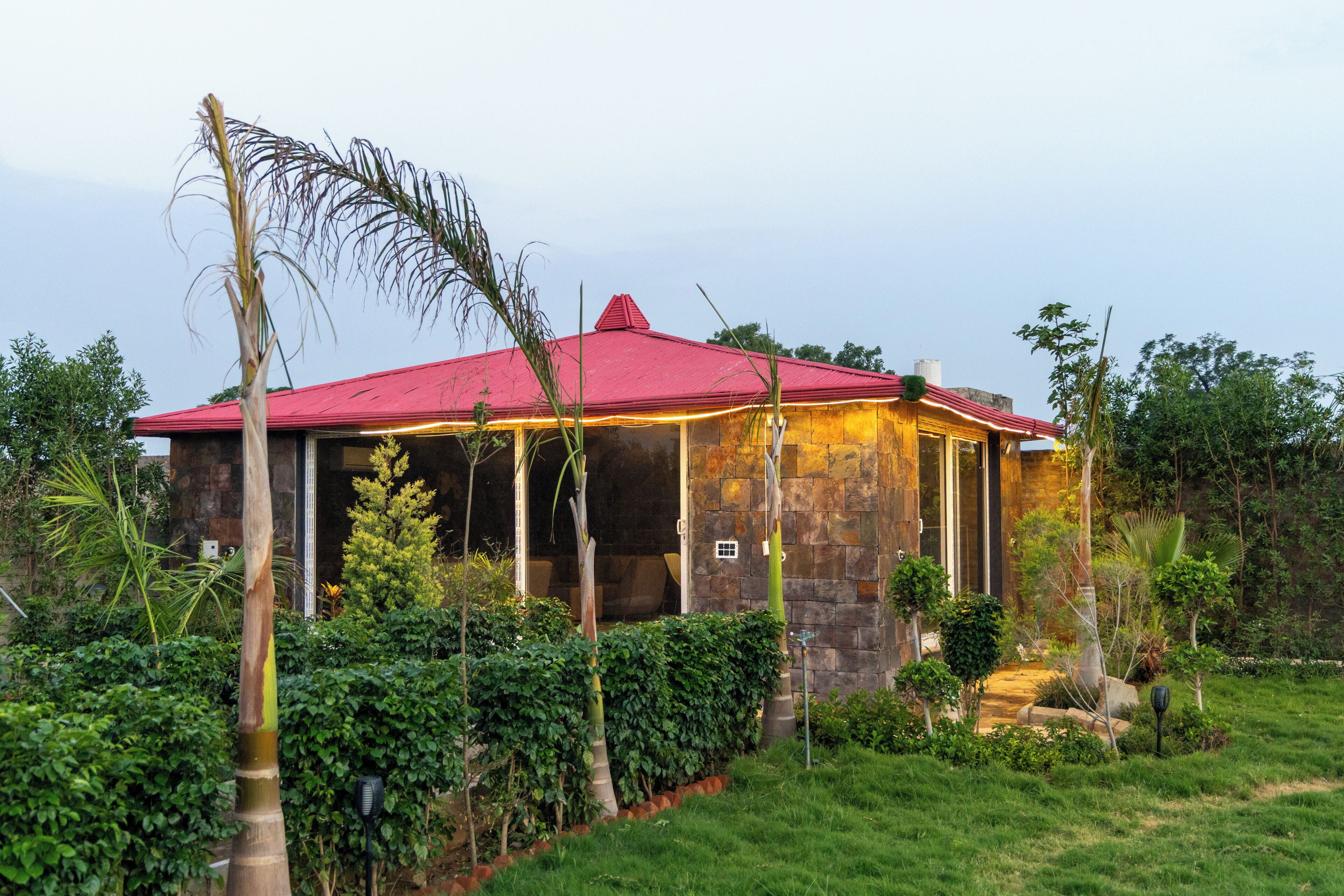 A house with a red roof, surrounded by lush greenery and a well-maintained garden.