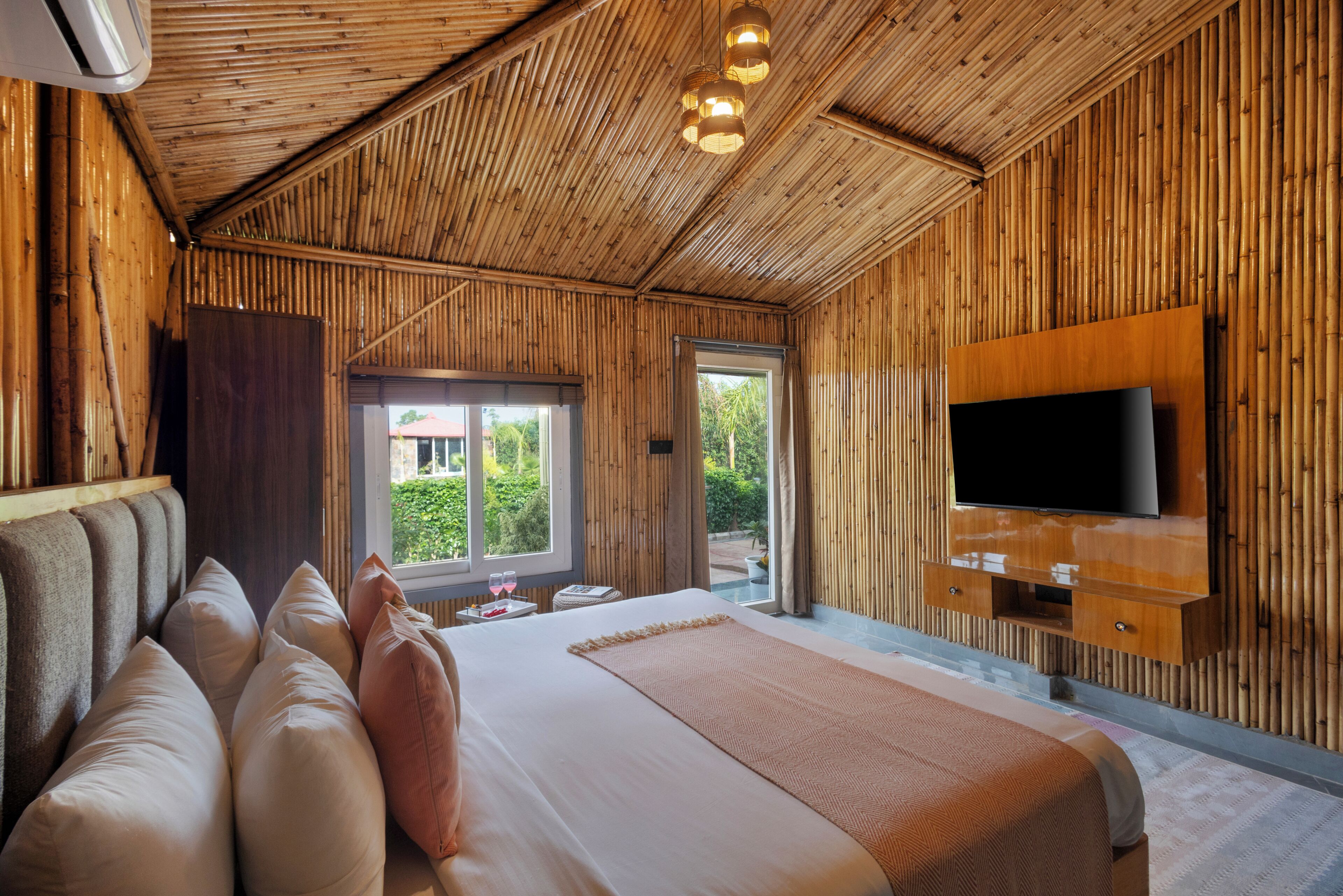 Una habitación con cama, televisión montada en la pared y ventana con vista a la vegetación.