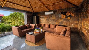 Una sala de estar moderna con pared de piedra, un ventanal grande y un ventilador de techo.