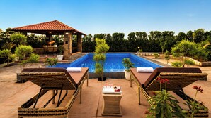 Una piscina con sillones de descanso y un pabellón.