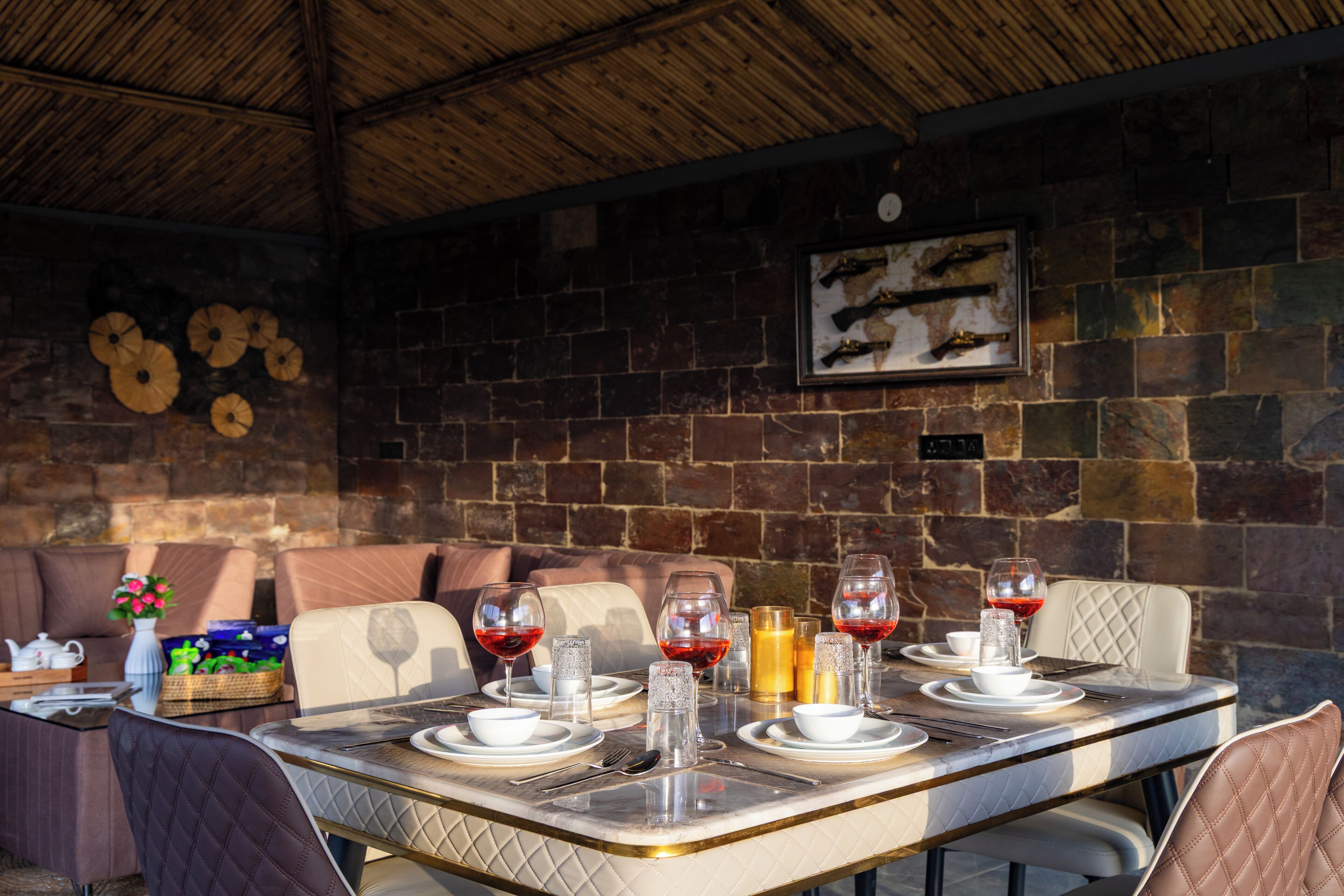Un comedor con una mesa dispuesta para cuatro personas, rodeado de paredes de piedra y un techo de madera.