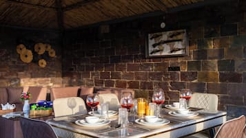 Un comedor con una mesa dispuesta para cuatro personas, rodeado de paredes de piedra y un techo de madera.