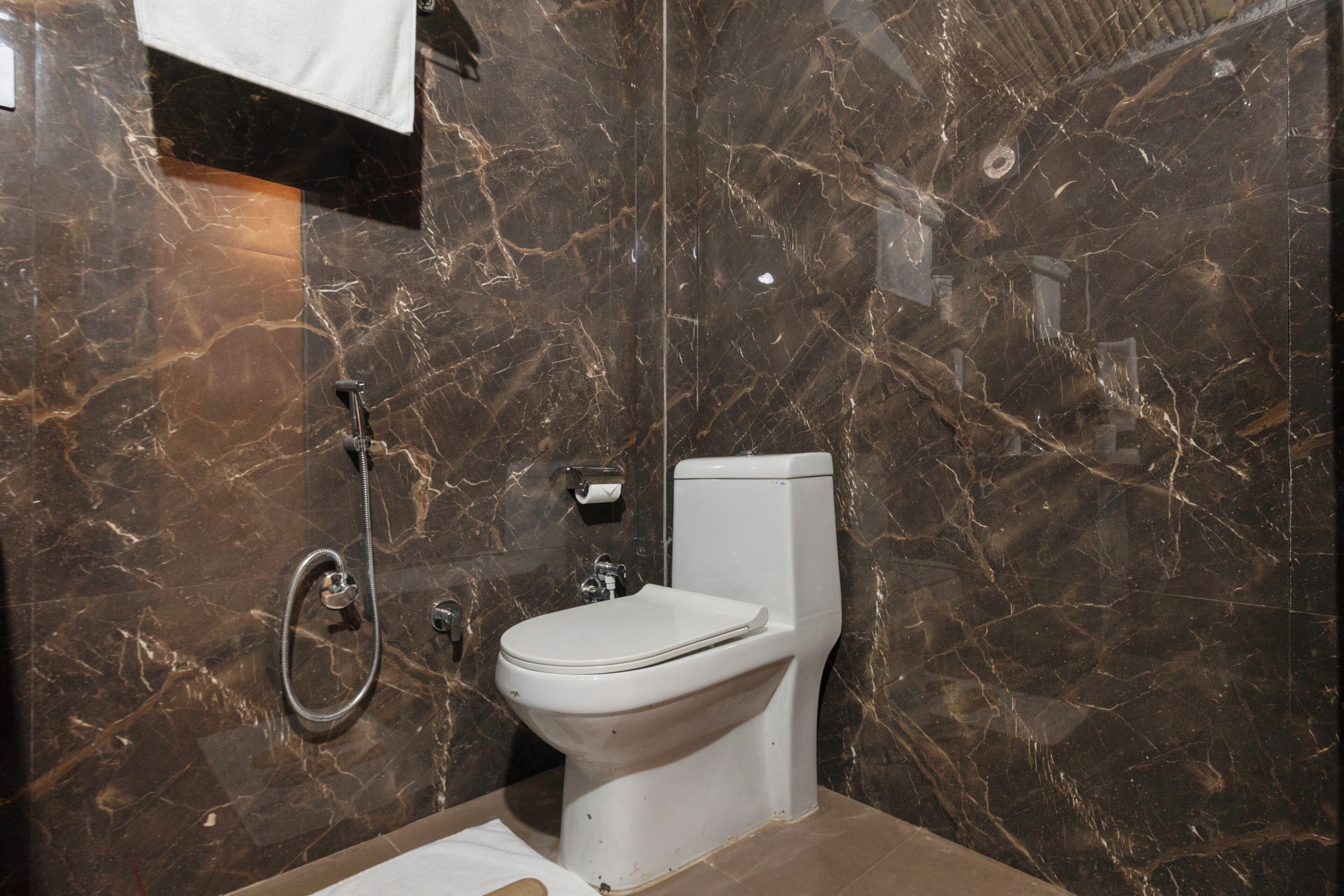 A bathroom with a marble wall, a toilet, and a sink.