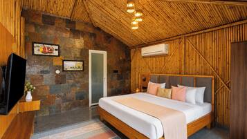 Un dormitorio con pared de piedra, cama con almohadas, televisor y unidad de aire acondicionado.