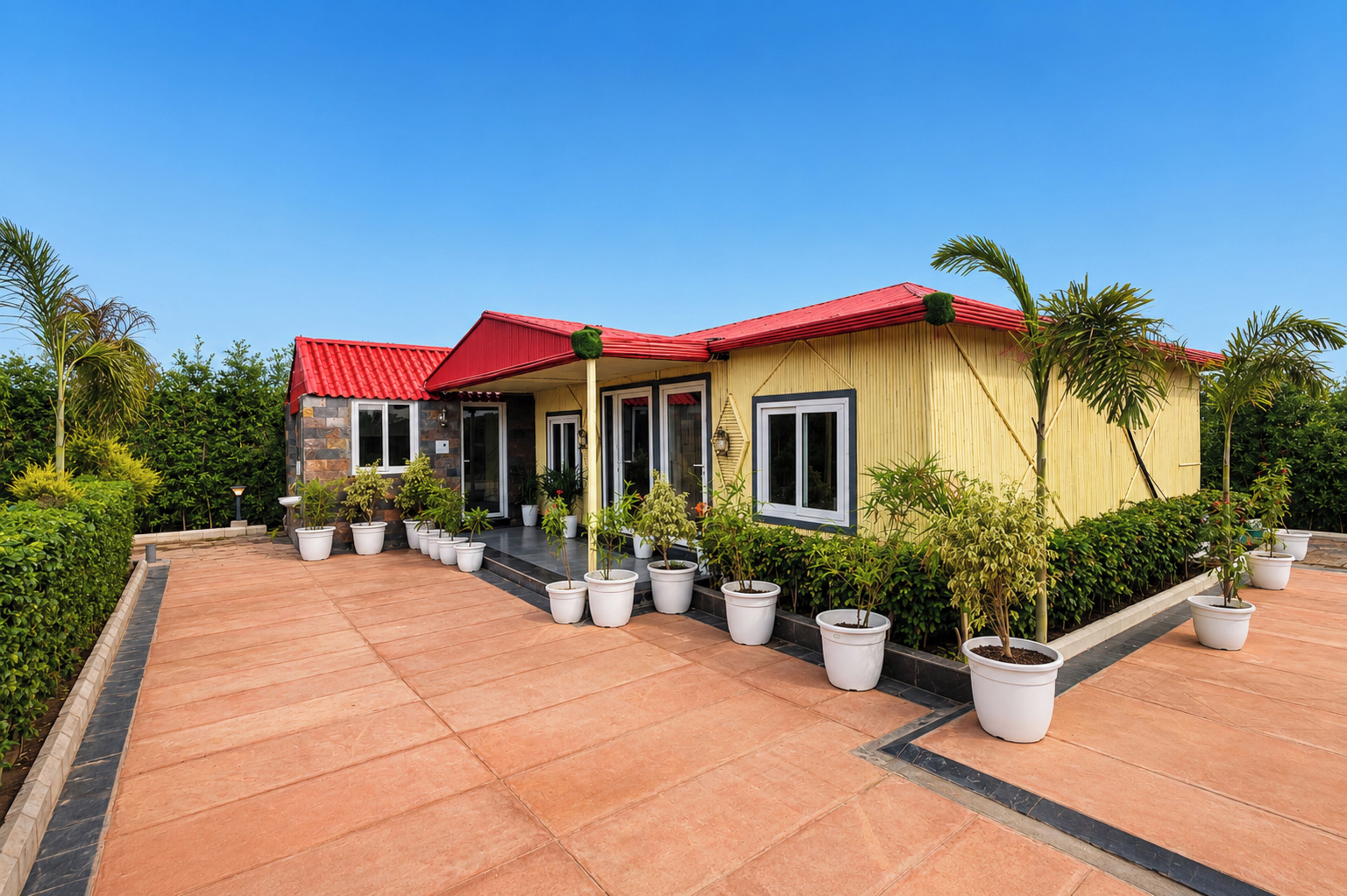 Una casa de dos pisos con techo rojo, varias ventanas y un camino de entrada pavimentado.