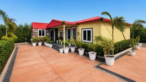 Una casa de dos pisos con techo rojo, varias ventanas y un camino de entrada pavimentado.