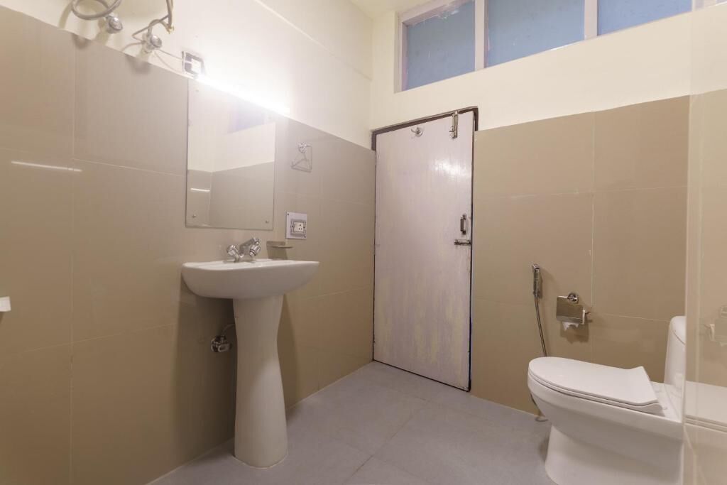 Ein Badezimmer mit einem Standwaschbecken, einer Toilette und einer Tür.