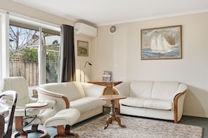 Ein Wohnzimmer mit einer Couch, Sesseln, einem kleinen Tisch und einem Bild an der Wand.