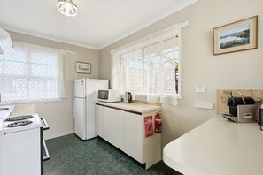 A compact kitchen with a refrigerator, microwave, and a coffee machine on the counter. - King`s Corner Retreat (Sandy Bay)