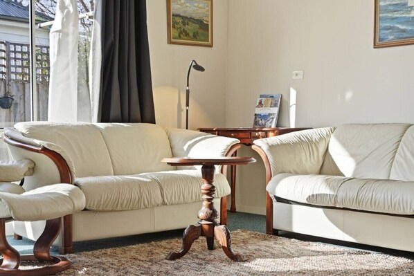 Ein Wohnzimmer mit einem beigen Sofa, einem Holztisch und einer Lampe.