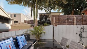 Eine Terrasse mit Tisch und Stühlen, einem Holzzaun und einer Palme.