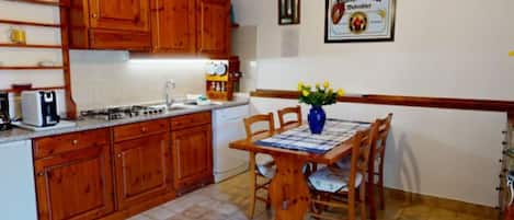 A kitchen with wooden cabinets, a dining table with chairs, and a hanging light fixture.