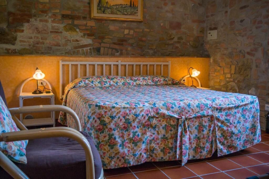 Een slaapkamer met een bed, twee bedlampen, een stoel en een bakstenen muur.