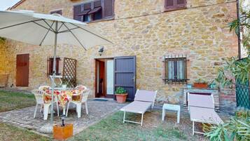 Edificio de piedra con un patio amoblado y una mesa.