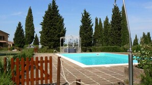 A swimming pool with a wooden fence, a gazebo, and tall trees in the background. - Toscana Vacanze (MONTAIONE)
