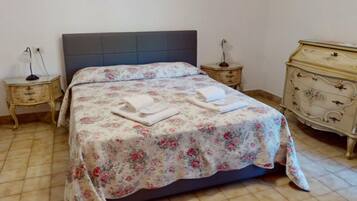 Una cama con cubrecama floral, dos mesitas de noche y un aparador.