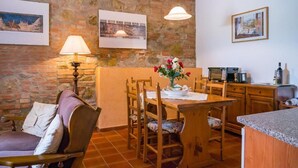 A dining area with a stone wall, wooden furniture, and artwork. - Toscana Vacanze (MONTAIONE)