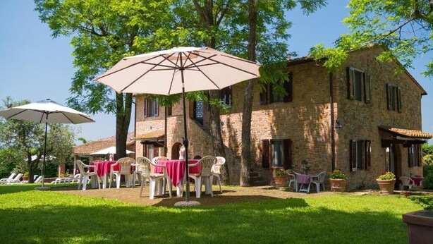 A stone building with outdoor seating and umbrellas. - Toscana Vacanze (MONTAIONE)
