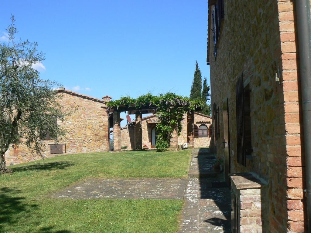 Un patio con edificios de piedra, césped y un muro de ladrillo.
