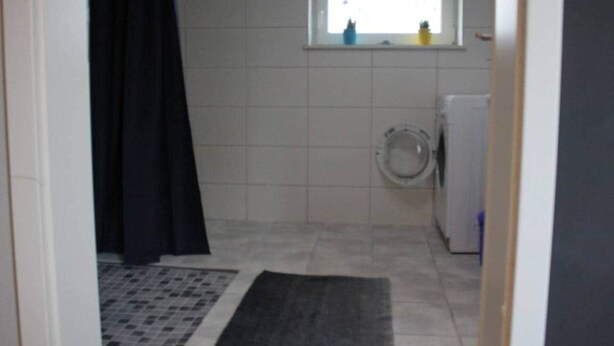Pieni kylpyhuone, jossa on wc, ikkuna ja pesukone.